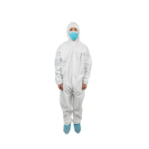 Person in a white hooded protective coverall, blue face mask, and blue shoe covers standing against a plain background Person in a white hooded protective coverall, blue face mask, and blue shoe covers standing against a plain background