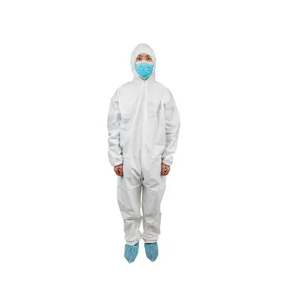 Person in a white hooded protective coverall, blue face mask, and blue shoe covers standing against a plain background