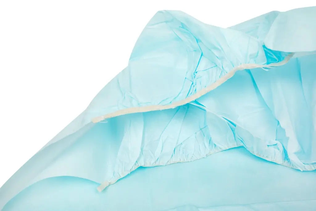 Close-up of light blue disposable protective gown material with elastic cuffs and gathered seams on a white background.