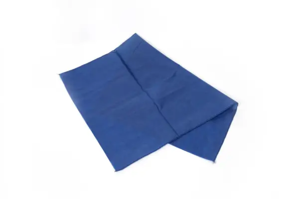 Folded blue fabric cloth on a white background A rectangular blue fabric cloth lies loosely folded on a clean white background, showing stitched edges and soft creases.