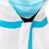 Close-up of worker wearing medical protective gear Close-up view of a person in a blue surgical mask and white protective coveralls against a plain background.
