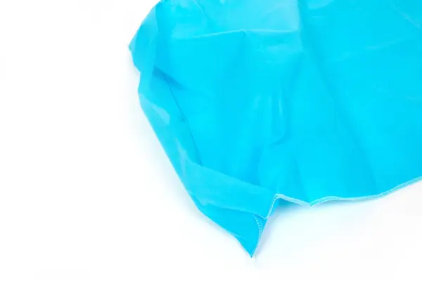 Close-up of bright blue nonwoven fabric Bright blue semi-transparent nonwoven fabric shown in close-up, with folded layers and stitched edge on white background.