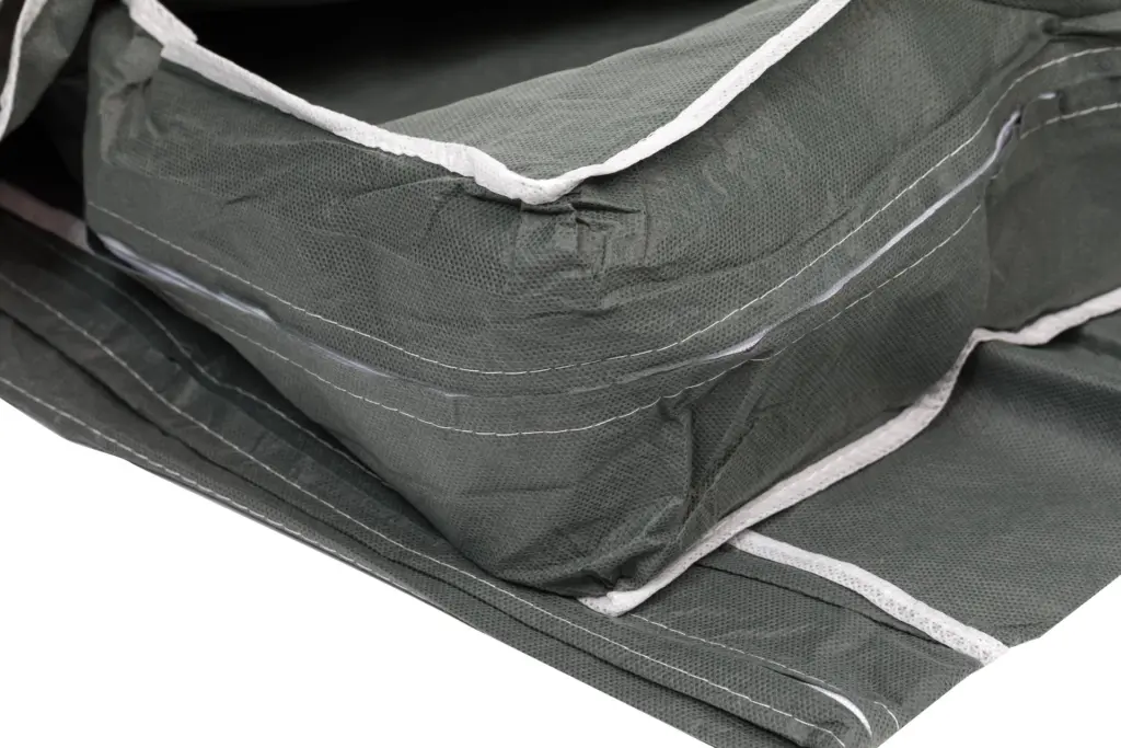 Close-up of folded dark green fabric organizers featuring textured material, white edging, stitched seams, and layered panels.