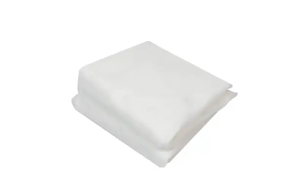 A neatly folded stack of soft white fabric rests against a plain white background, showing layered edges and smooth texture.