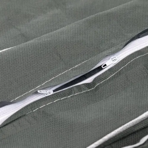 Close-up of a partially open white zipper sewn into textured dark green mesh fabric with contrasting white stitching.