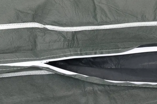 Close-up of a green mesh fabric zipper seam Open white zipper set into dark green mesh fabric, showing stitched seams and black inner lining in close detail.