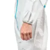 Close-up of a hand in a white protective suit A person’s relaxed hand hangs from a white protective coverall with an elastic cuff and blue seam against a plain background.