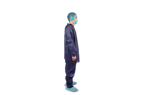 Healthcare worker wearing full protective equipment Side-profile healthcare worker wearing a blue protective gown, face mask, hair cover, gloves, and shoe covers