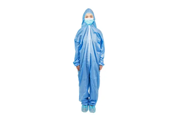 Healthcare worker wearing full protective coverall Healthcare worker standing against a white background in a blue hooded protective coverall, face mask, and shoe covers.