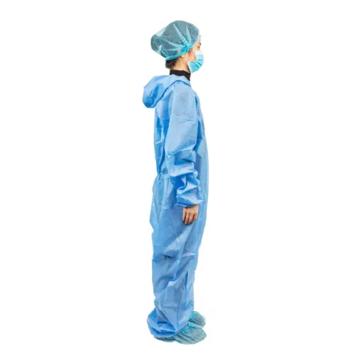 Medical worker wearing blue protective coveralls Healthcare worker in blue protective coveralls, hair cover, face mask, and shoe covers stands in profile against white