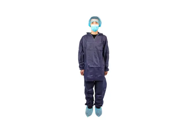 Medical worker wearing full protective coveralls Person wearing a dark protective coverall suit, blue hair cover, face mask, and disposable shoe covers against a white background