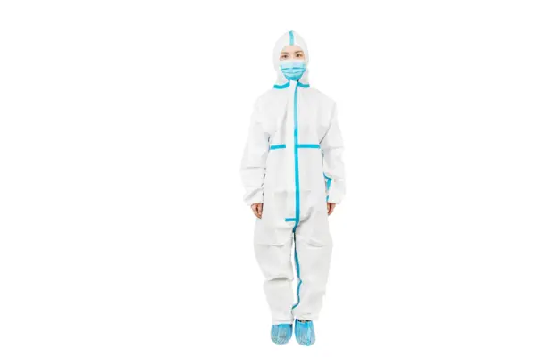 Medical worker in protective suit and face mask Medical worker standing against a white background in a white protective coverall with blue seams, mask, hood, and shoe covers.