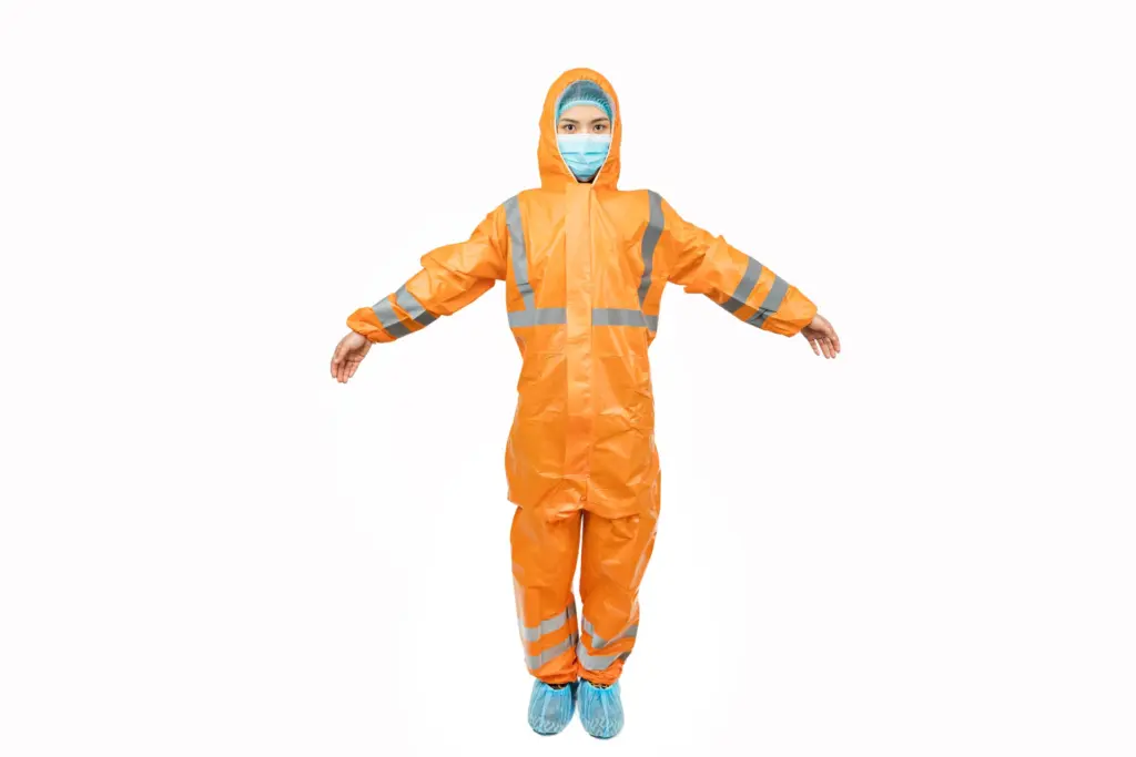 Person in an orange hooded protective coverall with reflective stripes, face mask, hairnet, and blue shoe covers