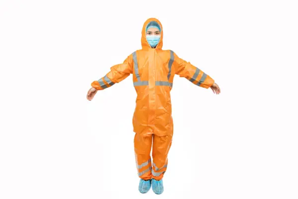 Worker wearing an orange protective coverall Person in an orange hooded protective coverall with reflective stripes, face mask, hairnet, and blue shoe covers