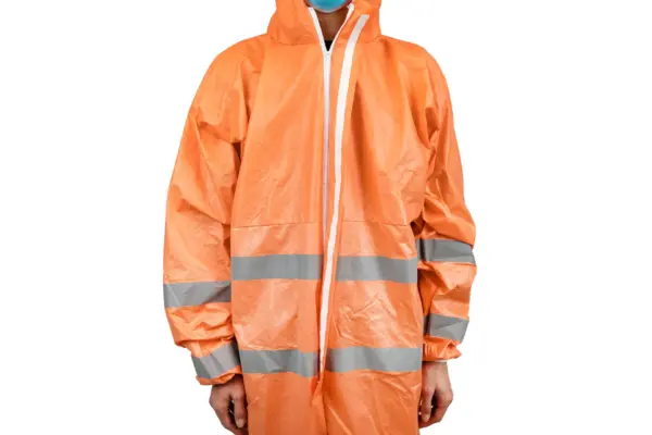 Orange reflective coverall worn against a white background Person wearing an orange hooded protective coverall with silver reflective bands and a blue face mask on white