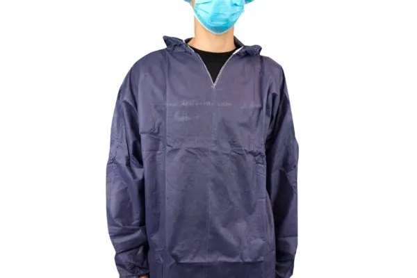 Person wearing a protective gown and face mask Person shown from the shoulders down wearing a dark blue disposable protective gown and light blue surgical face mask.