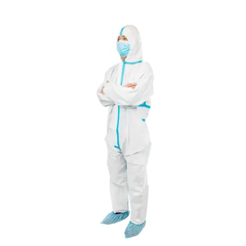 Worker in protective suit and face mask Person standing with folded arms in a white protective coverall, blue surgical mask, and blue shoe covers.