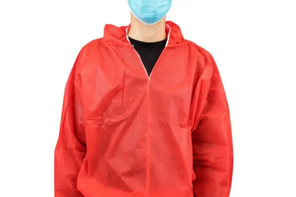Person wearing a red protective gown and mask Person shown from the shoulders down wearing a red hooded protective gown over black clothing and a blue surgical mask