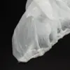 Translucent protective cover on a black surface Crinkled translucent disposable plastic cover with a gathered elastic edge resting on a black background