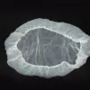 Transparent disposable shower cap on black background Transparent disposable plastic shower cap with an elastic gathered edge, laid flat against a plain black background.