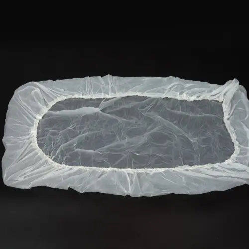 Translucent rectangular plastic cover with gathered elastic edging laid flat against a black background.