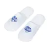 Pair of white open-back fabric spa slippers displayed on a plain white background, each featuring a blue printed logo.