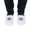 Person wearing white closed-toe Spa Village slippers over dark socks and navy trousers against a plain white background.