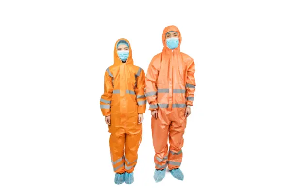 Two workers in orange protective suits and masks Two people wear orange hooded protective suits, face masks, hair covers, reflective bands, and blue shoe covers on white.